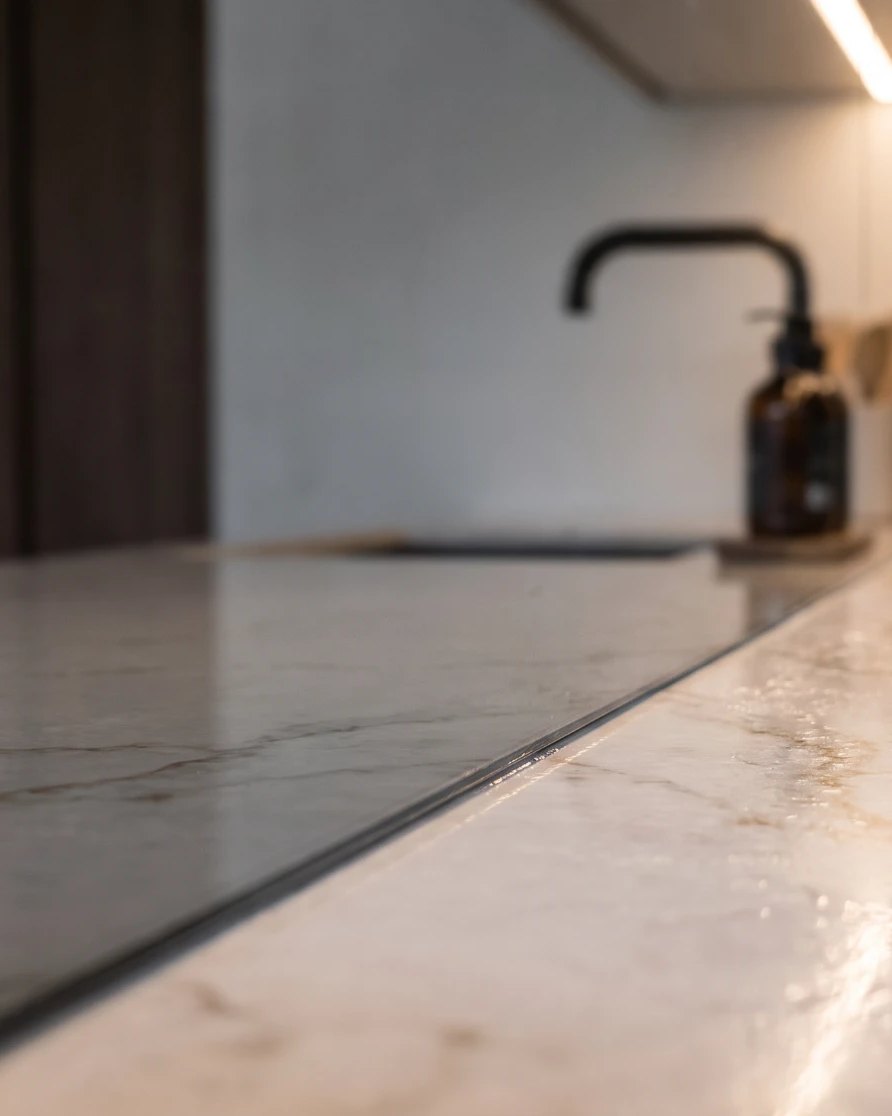 Close-up of a neat sealed joint where the glass splashback meets the worktop