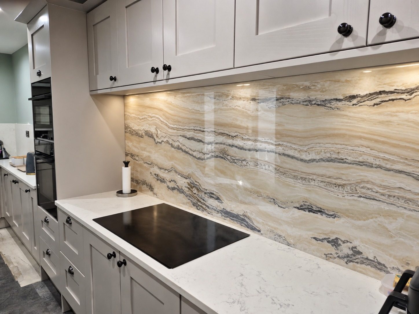 Full-length marble-effect glass splashback in a white kitchen